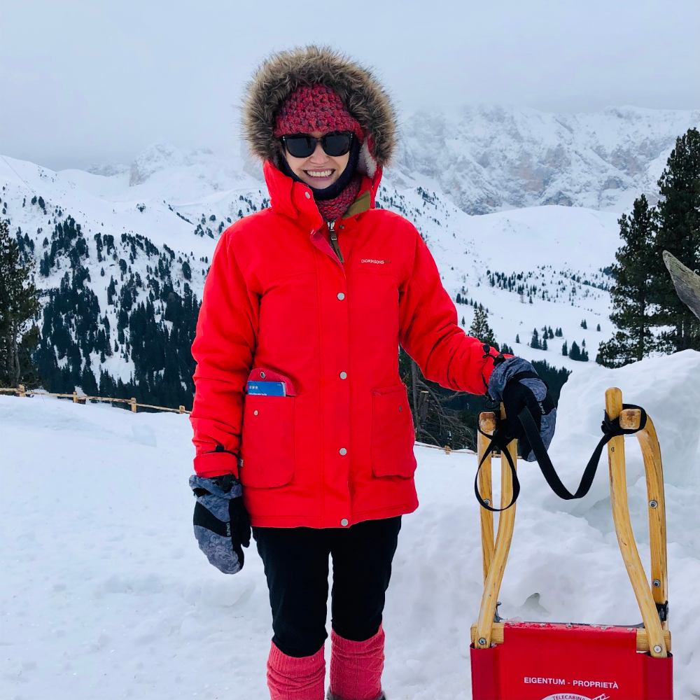 Nicole Lantz in a parka holding a sledge at the top of a snowy mountain